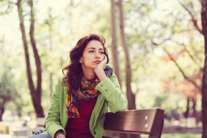 woman-sitting-on-park-bench-looking-sad-and-contemplative